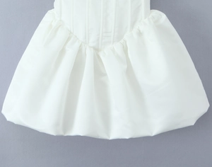 Close-up of white satin dress detailing boning structure and gathered pleats at the waist