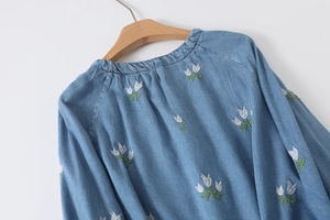 Détail du chemisier bleu à manches longues avec broderie de tulipes et encolure ronde plissée