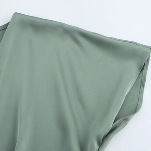 Détail du tissu satiné vert sauge avec une brillance soyeuse et des coutures fines