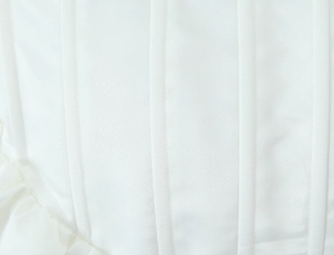 Detail of white corset dress showing vertical boning structure and ruffled hem edges