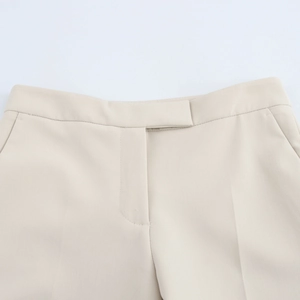 Detail of high-waist beige suit trousers featuring side pockets and a hidden placket