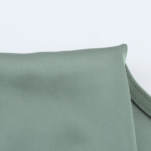 Close-up detail of sage green satin dress featuring double-needle stitching and fine texture