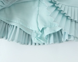 Detail of light blue pleated mini skirt showing the built-in safety shorts and honeycomb fabric