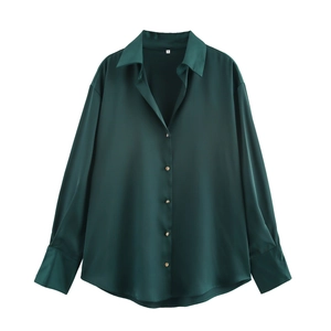 Detailed macro view of dark green satin shirt featuring polished gold metal buttons