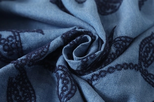 Détail de chemise en denim bleu montrant une broderie paisley marine et le tissage