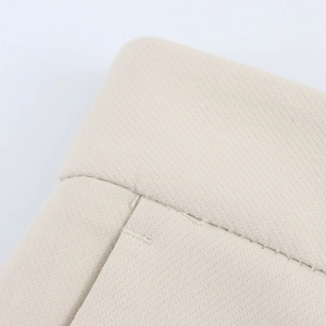 Close-up of fine woven fabric and precise stitching on beige suit trousers detail