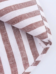 Gros plan d'une chemise rayée marron et blanc montrant la texture du tissu et couture