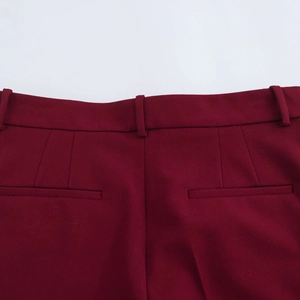 Gedetailleerde weergave van bordeauxrode pantalon met hoge taille en riemlussen