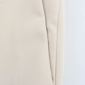 Detail of beige suit trousers showing the slanted side pocket and precision stitching