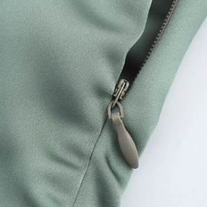 Detail view of the high-quality invisible zipper and smooth satin fabric on the green dress