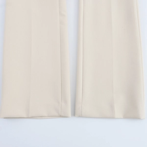 Detailed close-up of beige trousers featuring central crease lines and neat hem stitching
