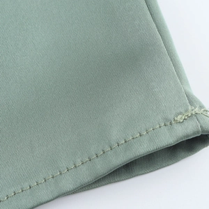 Close-up of light green satin fabric showing fine twill texture and single-needle stitching