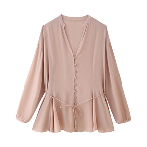Detail of pink V-neck blouse featuring golden buttons and adjustable drawstring waist