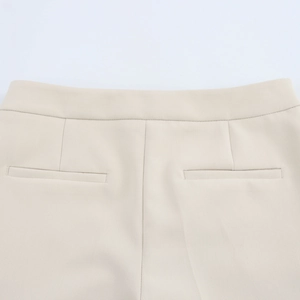 Detailed view of the tailored waist and welt back pocket on cream dress trousers