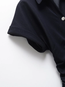 Detailed view of dark denim dress collar with silver metal button and cuffed short sleeve