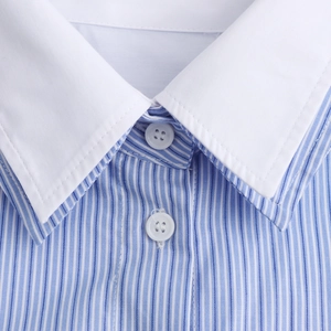 Detail of blue and white striped shirt featuring contrast white collar and button neckline