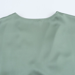 Detail of the high-quality round neckline and smooth satin fabric on a sage green dress