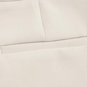 Close-up of high-quality stitching and fabric texture on beige lapel blazer pockets
