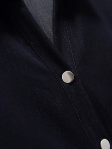 Close-up of navy blue denim dress fabric with twill texture and silver metal buttons