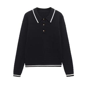Close-up of black knit polo shirt showing contrast white stripes and gold buttons