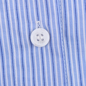 Detailed macro view of white button on blue and white striped long sleeve shirt