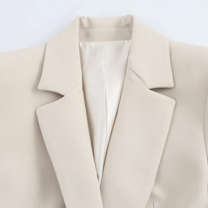 Detailed close-up of notch lapel and fine stitching on beige women blazer