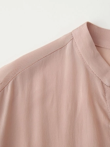 Detail view of pink silk shirt showing fine shoulder stitching and V-neckline texture