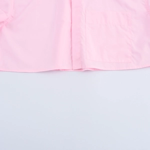 Close-up of pink short-sleeve shirt showing cotton fabric texture and chest pocket detail
