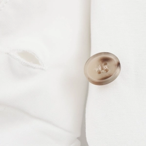 Detailaufnahme des braun marmorierten Knopfes und Webstoffs der High-Waist-Hose