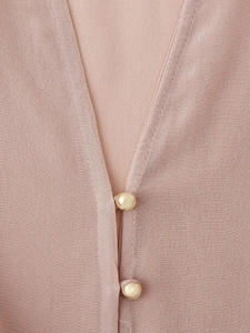 Close-up of V-neckline and gold button details on pink crepe long sleeve shirt