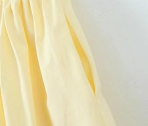 Detailansicht der unsichtbaren Seitentaschen und Taillenfalten am hellgelben Sommerkleid