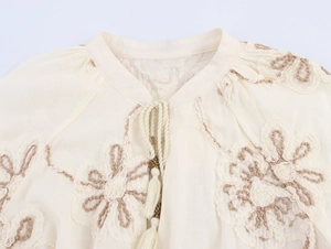 Close-up of floral embroidery detail and tassel drawstring on the stand collar shirt
