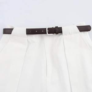 Detailansicht der weißen High-Waist-Hose mit schmalem braunem Ledergürtel und Silberschnalle