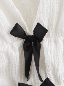 Vue détaillée du tissu blanc seersucker et du nœud élégant en satin noir décoratif