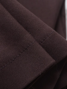 Close-up of deep brown fabric showing detailed twill texture and neat stitching seams