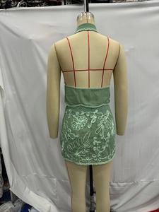 Dettaglio retro del set top allacciato al collo e gonna verde chiaro con ricami floreali