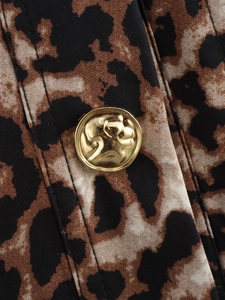 Macro detail of leopard print fabric featuring a gold metal button with animal relief