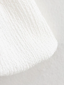 Gros plan du tissu gaufré blanc avec bordure ondulée délicate sur un haut sans manches