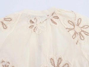 Detailed close-up of floral embroidery on off-white long sleeve shirt collar