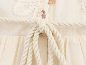 Detail of waist tie with woven cord, wooden button and delicate crochet lace trim