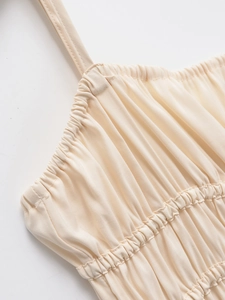 Detail of light beige camisole dress featuring gathered bodice and elastic smocking design