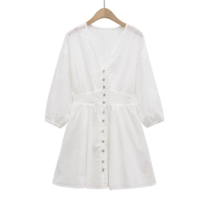 Détail de la broderie blanche et des boutons nacrés élégants sur la robe à col en V