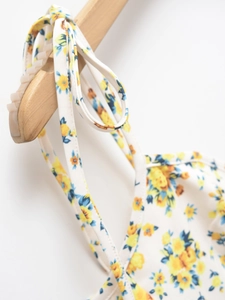 Close-up of floral print dress featuring adjustable shoulder ties and yellow flower pattern