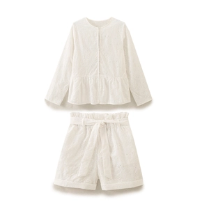 Dettaglio del ricamo in cotone bianco sul set camicetta e pantaloncini con cintura