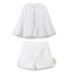 Detail of white cotton eyelet embroidery and tie-front closure on the long sleeve top