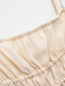 Macro shot of U-neckline with pleated details and thin straps on a beige summer dress