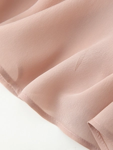 Detailed view of the soft pink chiffon shirt hem with clean stitching and draping