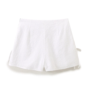 Detailed view of white high-waisted shorts with eyelet embroidery and side ribbon ties