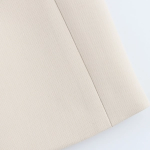 Detail of premium beige textile fabric showing fine weave texture and precise stitching