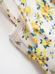 Close-up of thin shoulder straps and floral print details on a white summer dress
